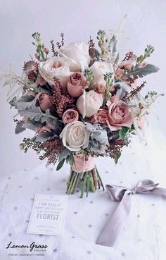 a bouquet of flowers sitting on top of a table next to a card and ribbon