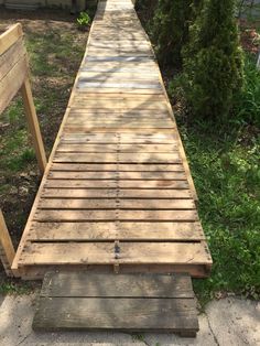 a wooden walkway in the middle of some grass