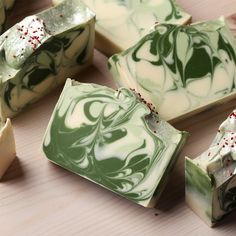 soaps with green and white swirled designs on them sitting on a wooden counter top