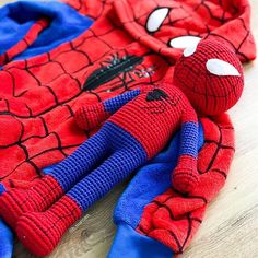 a spiderman sweater laying on top of a wooden floor next to a stuffed animal