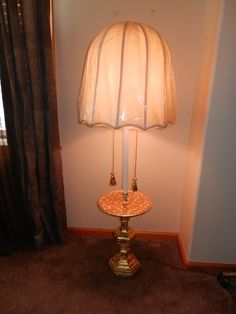 a lamp that is on top of a table in the corner of a room with curtains