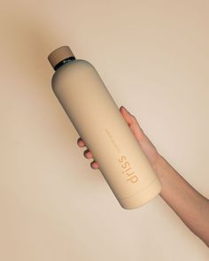 a hand holding a tan insulated water bottle