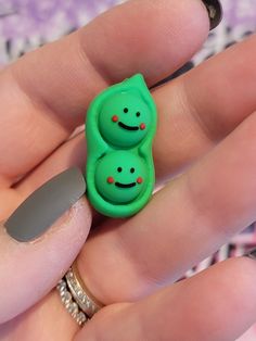 a person holding a green ring with two smiling faces on it's face and a gray nail