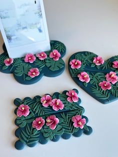 two heart shaped coasters with pink flowers on them and a photo frame in the background