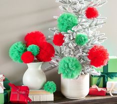 a white vase filled with red and green pom poms sitting on top of a table