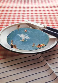 a plate with people floating in the water on it and two forks resting on top