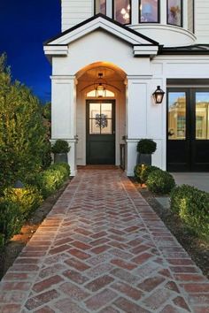 a white house with a black door and brick walkway leading to the front entrance at night