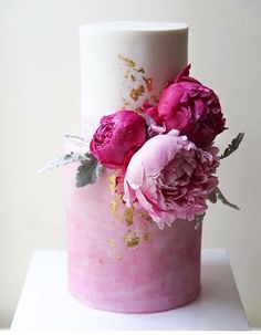 a pink and white cake with flowers on top