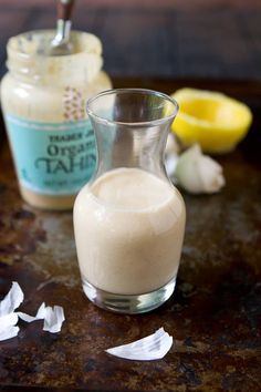 a glass pitcher filled with liquid sitting on top of a counter next to garlic and lemon wedges