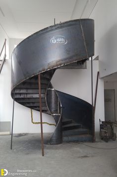 a large metal boat sitting on top of a floor next to a stair case in a building