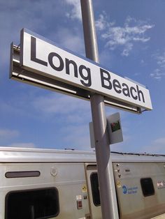 a long beach street sign next to a train