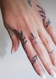 a woman's hand with tattoos on it and an arrow tattooed on the ring finger