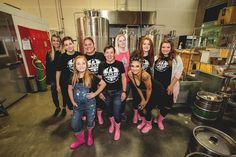 a group of people standing next to each other in front of some keg tanks