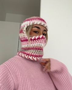 a woman wearing a pink and white knitted hat with a scarf around her face