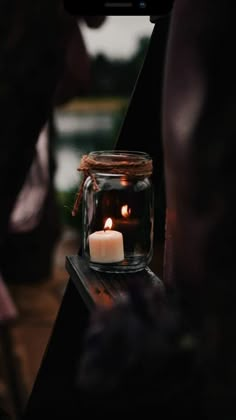 a candle is lit in a glass jar