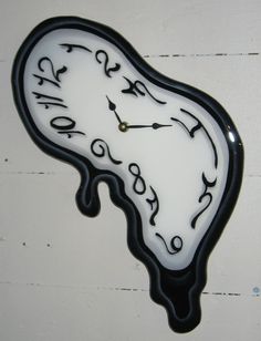 a black and white clock with writing on it's face is hanging from the wall