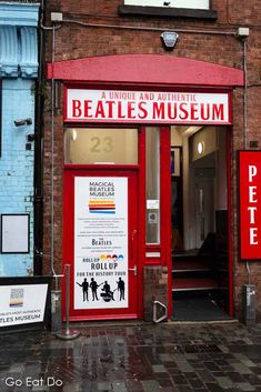 an entrance to the beatles museum on a brick building with red door and sign above it