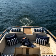 the back end of a boat with blue and white pillows on it's seats