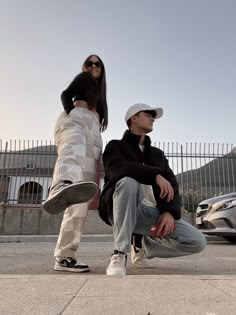 two people sitting on the ground with skateboards in their hands and one person standing behind them