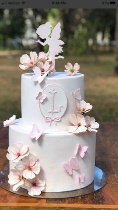 a white cake with pink flowers and butterflies on it