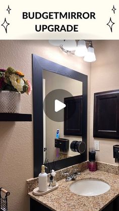 a bathroom with a large mirror above the sink and flowers on the counter in front of it