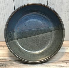 a black plate sitting on top of a wooden table next to a white board wall