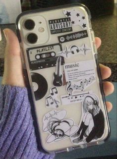 someone is holding up their phone case with stickers on it, and there are other things in front of them