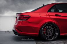 the rear end of a red mercedes c - class car with dark clouds in the background