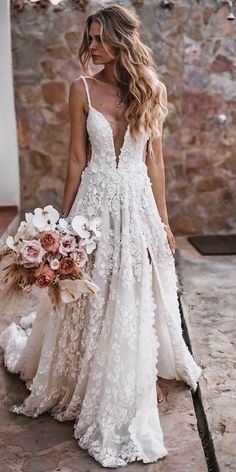 a woman in a wedding dress holding a bouquet and walking down the street with her back to the camera