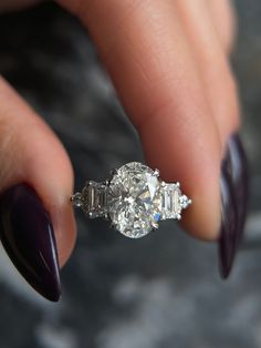 a woman's hand holding a diamond ring with two stones on the middle finger