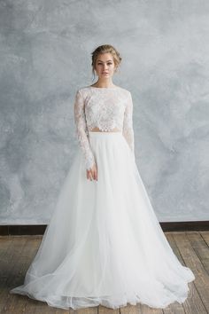 a woman in a white wedding dress standing on a wooden floor with her hands behind her back