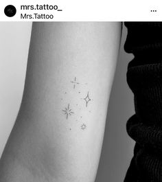 a small star tattoo on the left inner arm, with stars in the middle and behind it