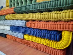 a stack of colorful mattresses sitting on top of a wooden floor