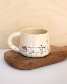 a white coffee cup sitting on top of a wooden board