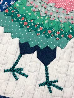 a close up of a quilted bird on a table top with flowers and polka dots