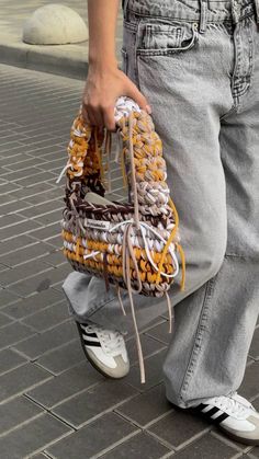 a person is holding a basket on the street while wearing white tennis shoes and jeans