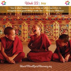 three young monks sitting on the floor with their hands in their pockets and laughing at each other