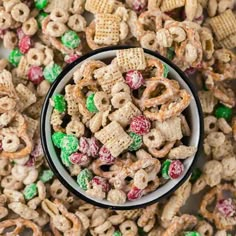 a white bowl filled with cheerios cereal next to green and red candy corn flakes