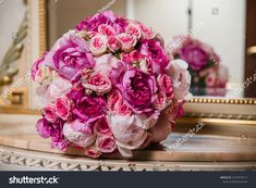 a bouquet of pink roses sits on a table in front of a mirror