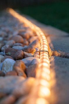 the light is shining on some rocks and stones in front of a bench with no one sitting at it