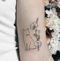 a cat and flower tattoo on the left inner arm, with flowers in the background