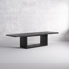 a black table sitting on top of a white floor in front of a gray wall