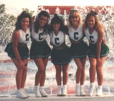 four cheerleaders posing in front of a fountain