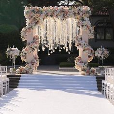 an outdoor wedding setup with flowers and chandeliers on the steps leading up to the aisle