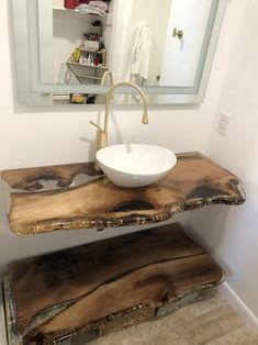 a bathroom sink sitting under a mirror next to a wooden counter with a bowl on it