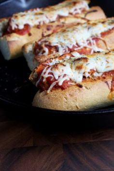 two slices of pizza sitting on top of a black pan covered in cheese and sauce