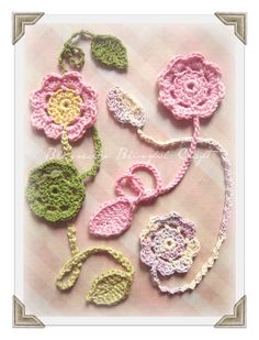 crocheted flowers and leaves are arranged on a tablecloth with an ornate border