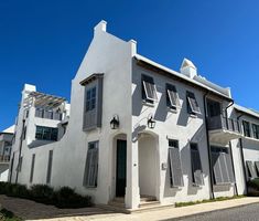 a white building with shutters on the windows