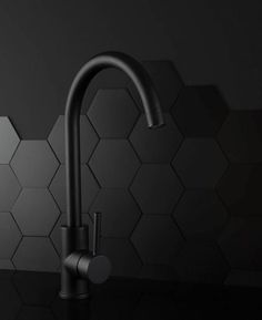 a kitchen faucet with black and white hexagonal tiles in the background