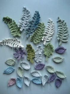 crocheted leaves are arranged on a white surface